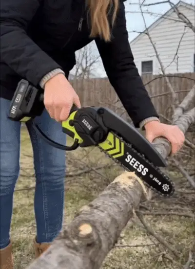 Person cutting a fallen log with a SEESE cordless mini chainsaw